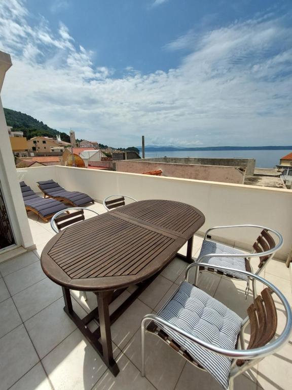 a wooden table and chairs on a balcony at Sea Holiday Houses in Drasnice