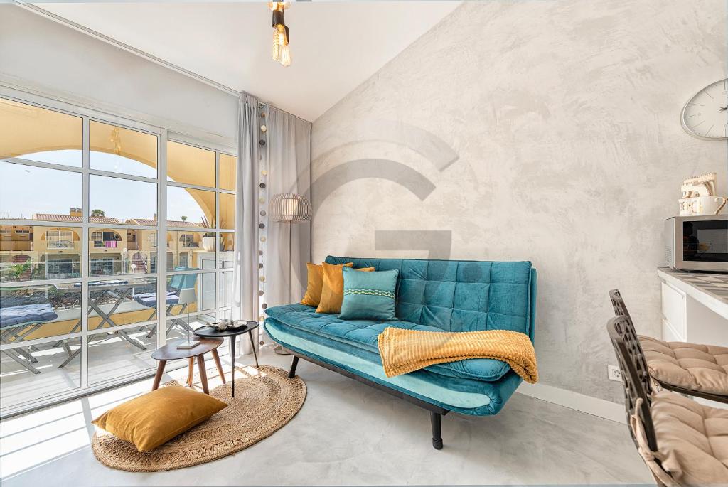 d'un salon avec un canapé bleu et d'un balcon. dans l'établissement Tisalaya Bright Apartment, à Maspalomas