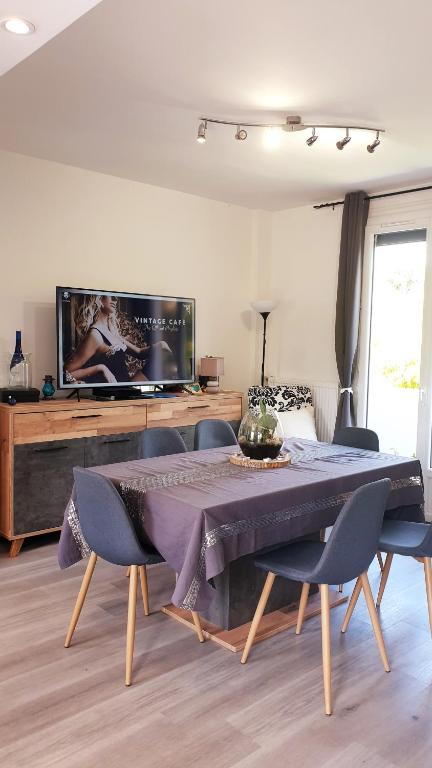 ein Wohnzimmer mit einem Tisch mit Stühlen und einem TV in der Unterkunft Chambre individuelle Jules in Agen