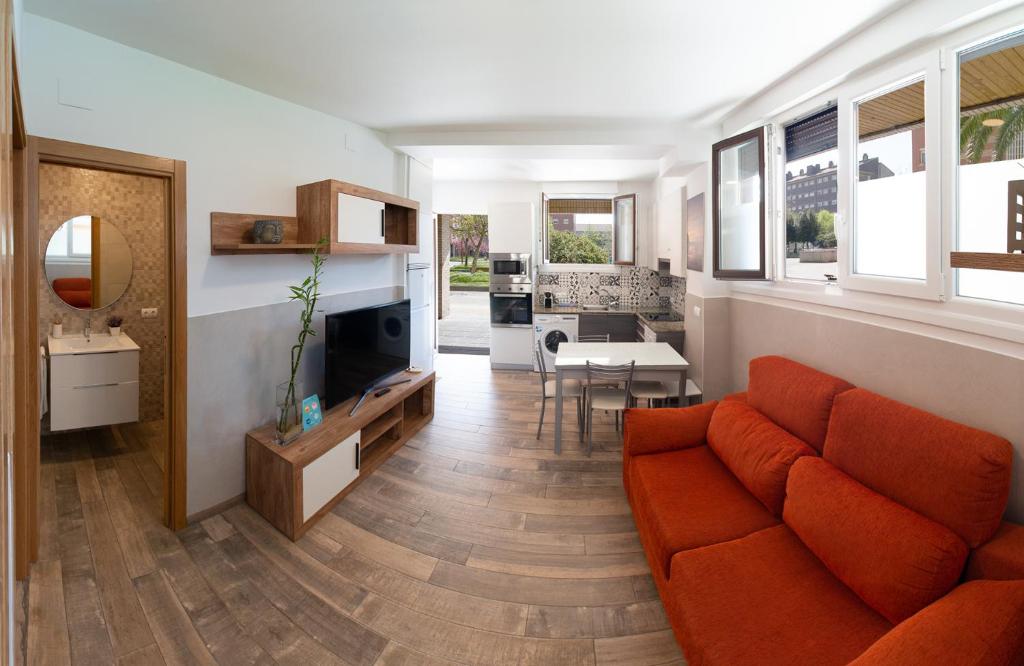 un salon avec un canapé orange et une cuisine dans l'établissement Apartamentos Lurralde, à Zarautz