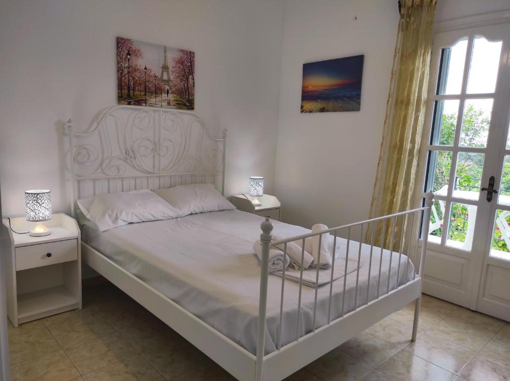 a bedroom with a white bed and two windows at Corfu countryside apartment in Potamós