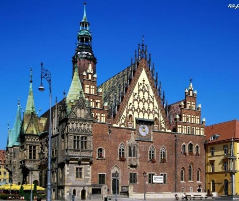 ein großes Backsteingebäude mit einem Uhrenturm darauf in der Unterkunft Rynek pod Fredrą in Breslau