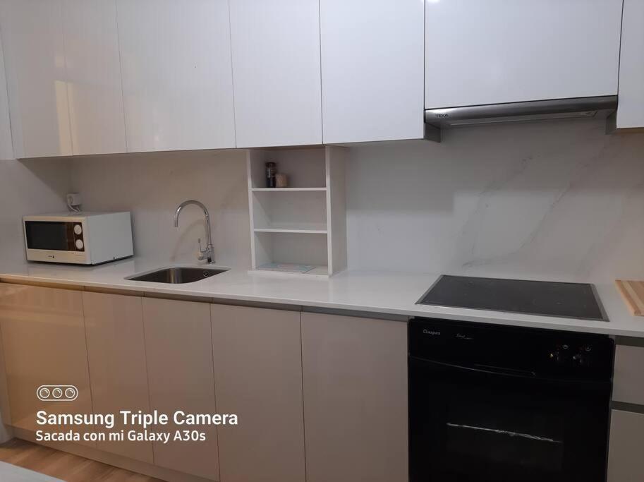 a kitchen with white cabinets and a sink and a microwave at Piso con preciosas vistas de vigo in Vigo