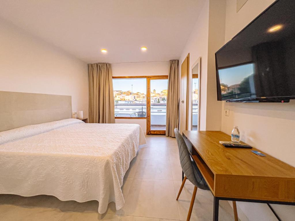 una camera d'albergo con letto, scrivania e TV di Hostal Sorbas a Sorbas