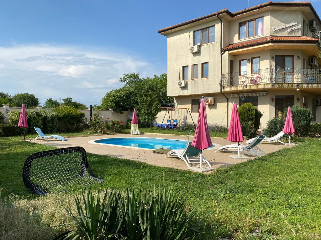 a house with a swimming pool with chairs and umbrellas at Guest House Golden Flake 4km from Bolata beach in Bŭlgarevo