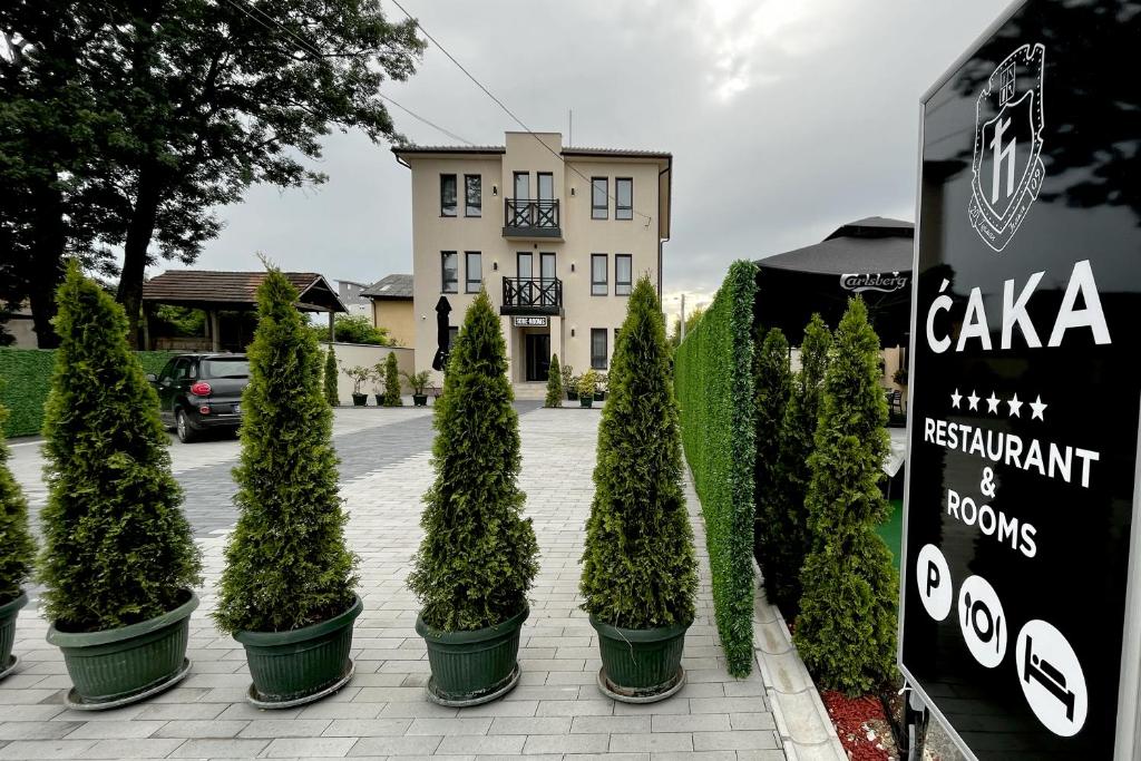 a row of potted trees in front of a building at ĆAKA Luxury Rooms & Restaurant in Ćuprija