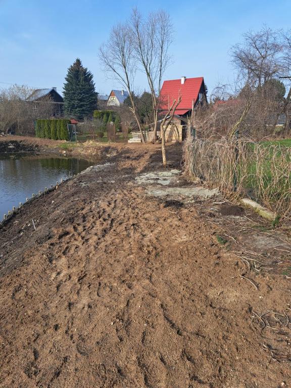 a dirt road next to a river with a house at OAZA in Olsztyn