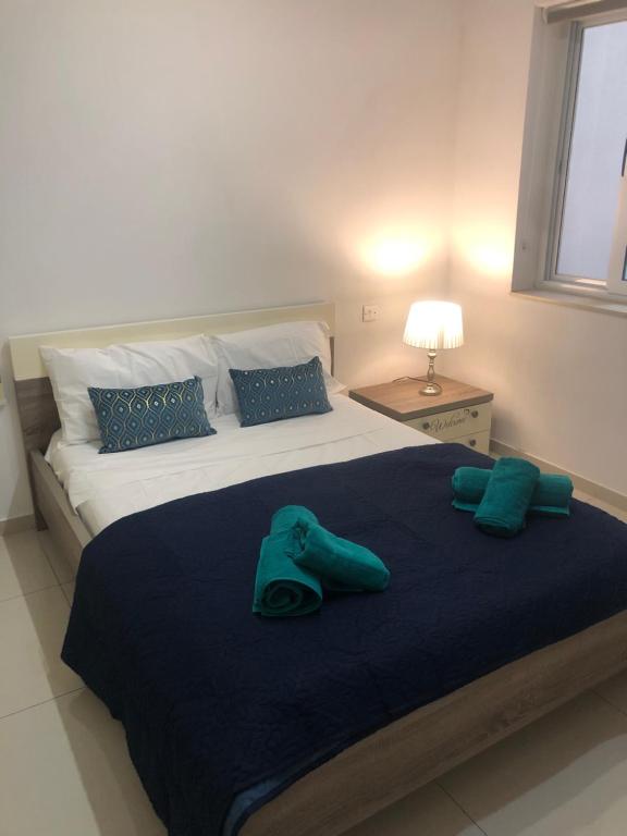 1 dormitorio con 1 cama grande y toallas verdes en Stanza vicino Paceville e San Giuliano, en Is-Swieqi