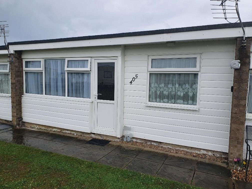 a white garage with a door and two windows at Hemsby Hideaway in Great Yarmouth