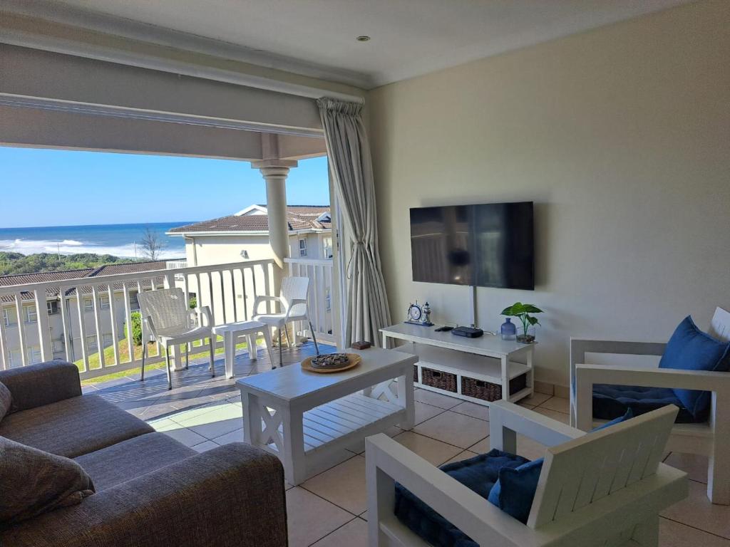 a living room with a couch and a television on a balcony at Hello Holiday at 4 Boboyi Mangrove Beach Estate in Port Shepstone