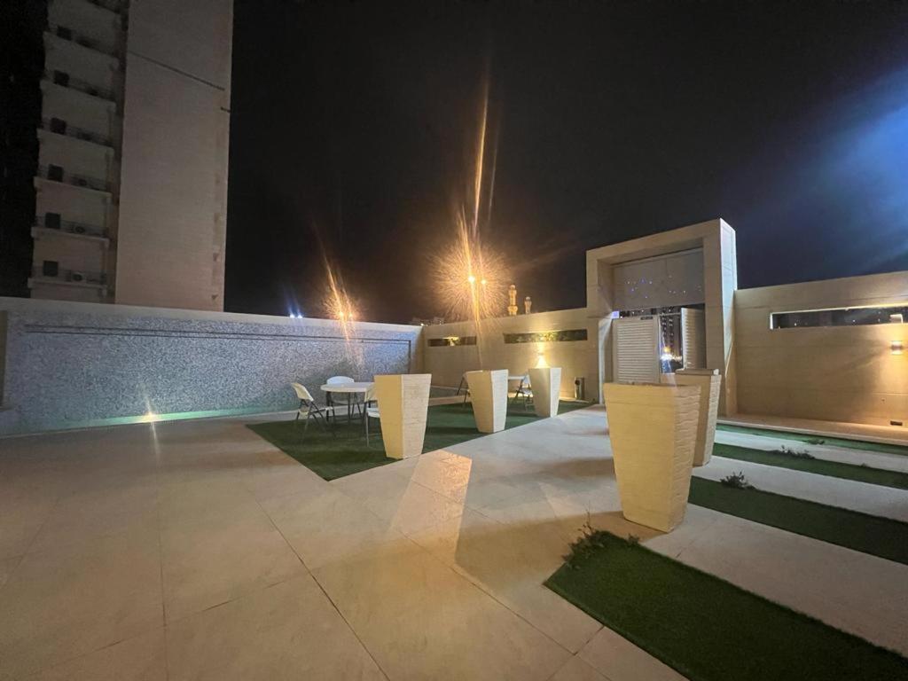 a patio with chairs and tables at night at White Luxury Suite Hotel in Kuwait