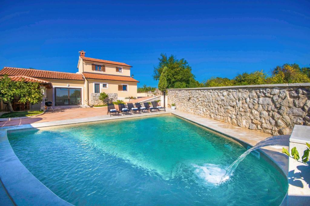 a swimming pool with a stone wall at Gorgeous Pool Villa with a fenced garden in Žminj