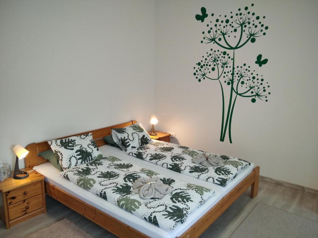 a bedroom with a bed with a plant on the wall at EszE Vendégszoba in Tata