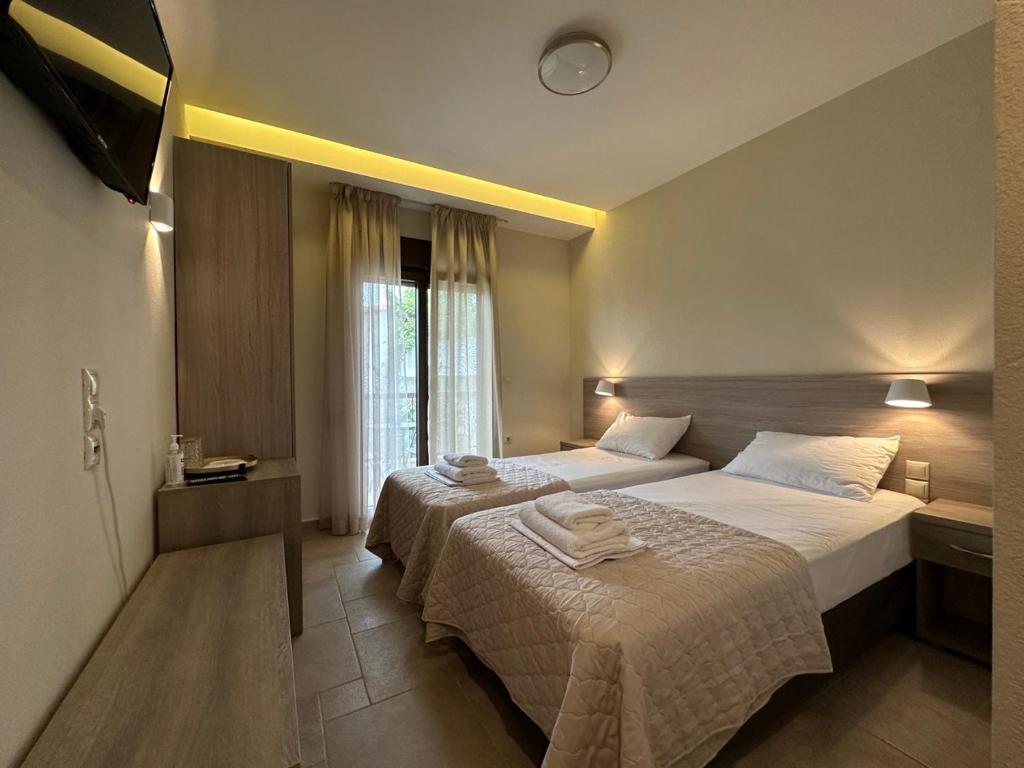 a hotel room with two beds and a television at Yulia Luxury Apartment in Ouranoupoli