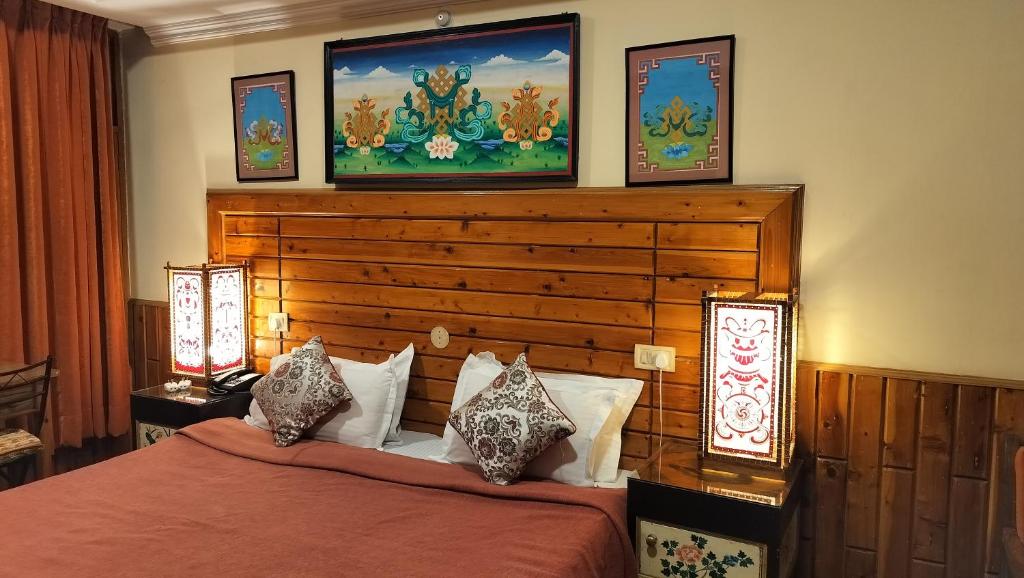 a bedroom with a bed with two lamps on the wall at Auspiscious Him View Hotel in McLeod Ganj