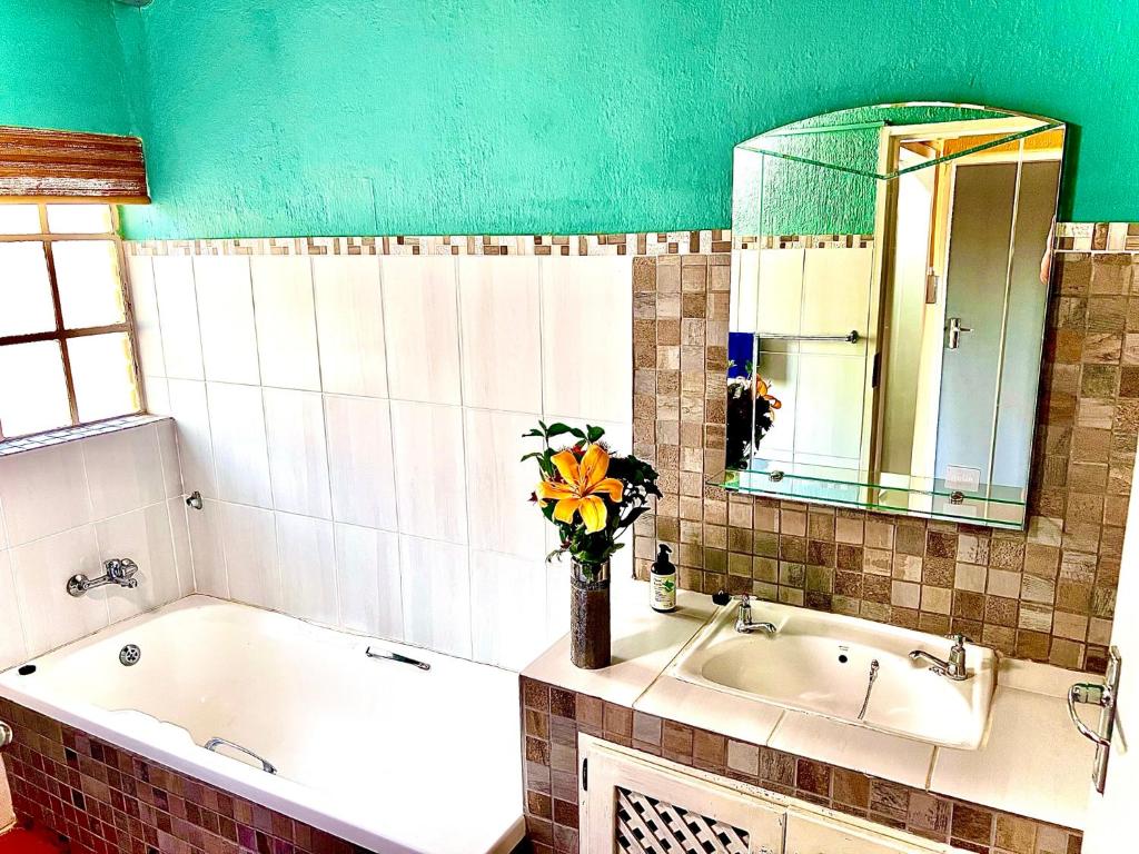 a bathroom with a tub and a vase of flowers at Kruger River View in Marloth Park