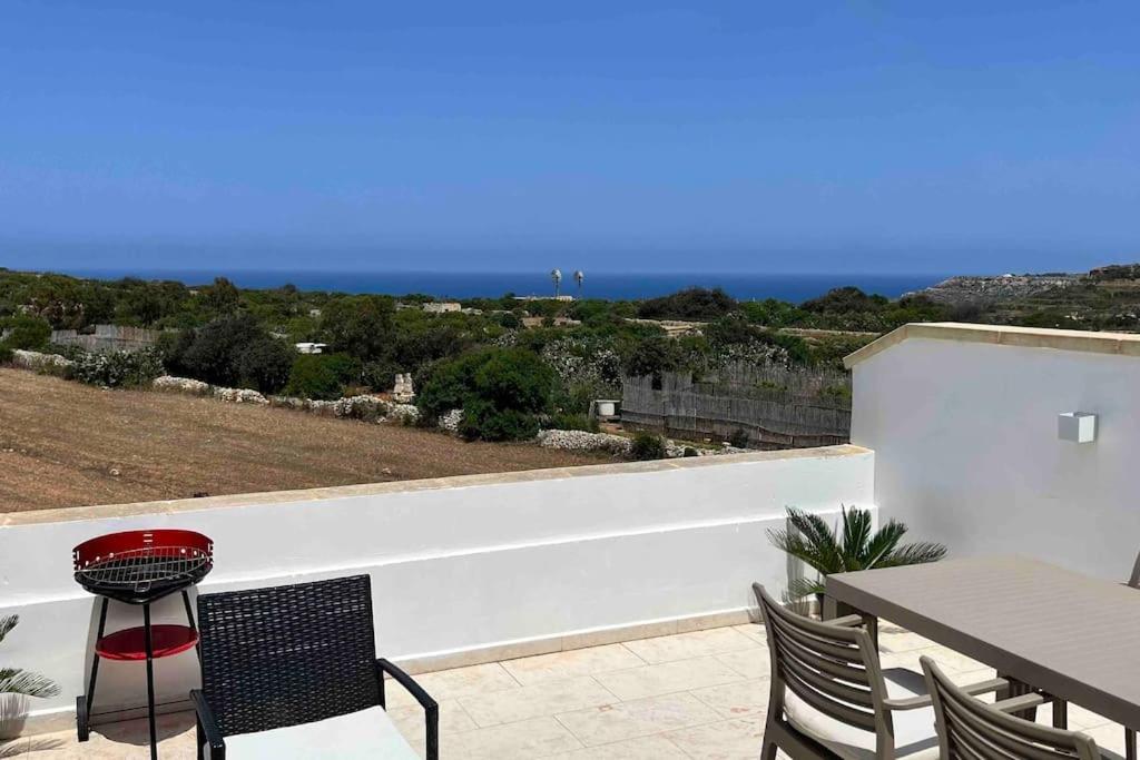 eine Terrasse mit einem Tisch und Stühlen sowie Meerblick in der Unterkunft Brand new 3-level sea view apartment near beach in Il-Pergla