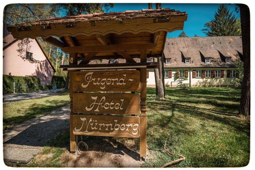 a sign in front of a house with a roof at Jugendhotel Nürnberg in Nürnberg