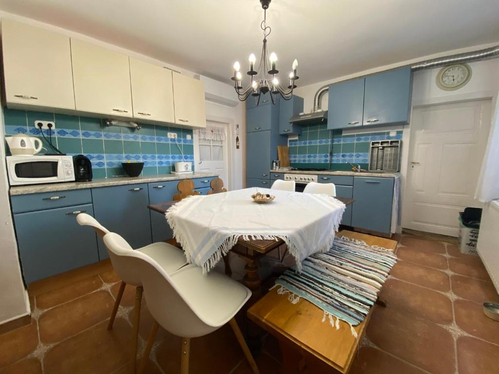 een keuken met blauwe kasten en een tafel en stoelen bij Lavender Cottage in Balatongyörök