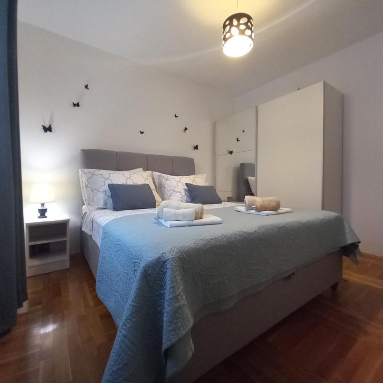 a bedroom with a large bed with a blue blanket at Apartman P&amp;M in Makarska