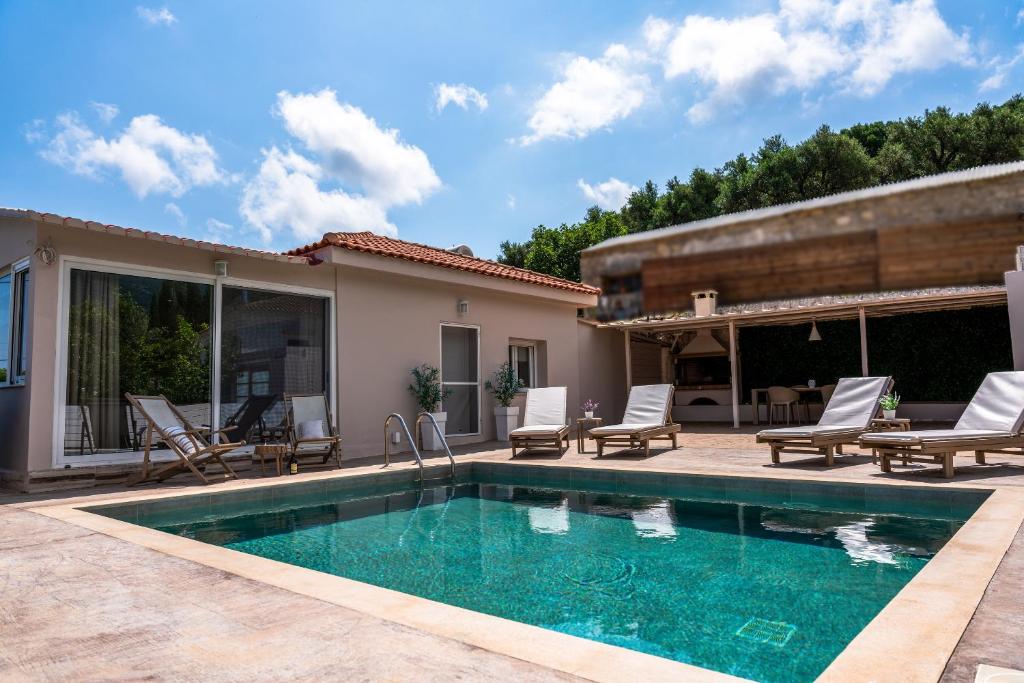 a swimming pool with chairs and a house at Casa Di Terra in Pigadhákia