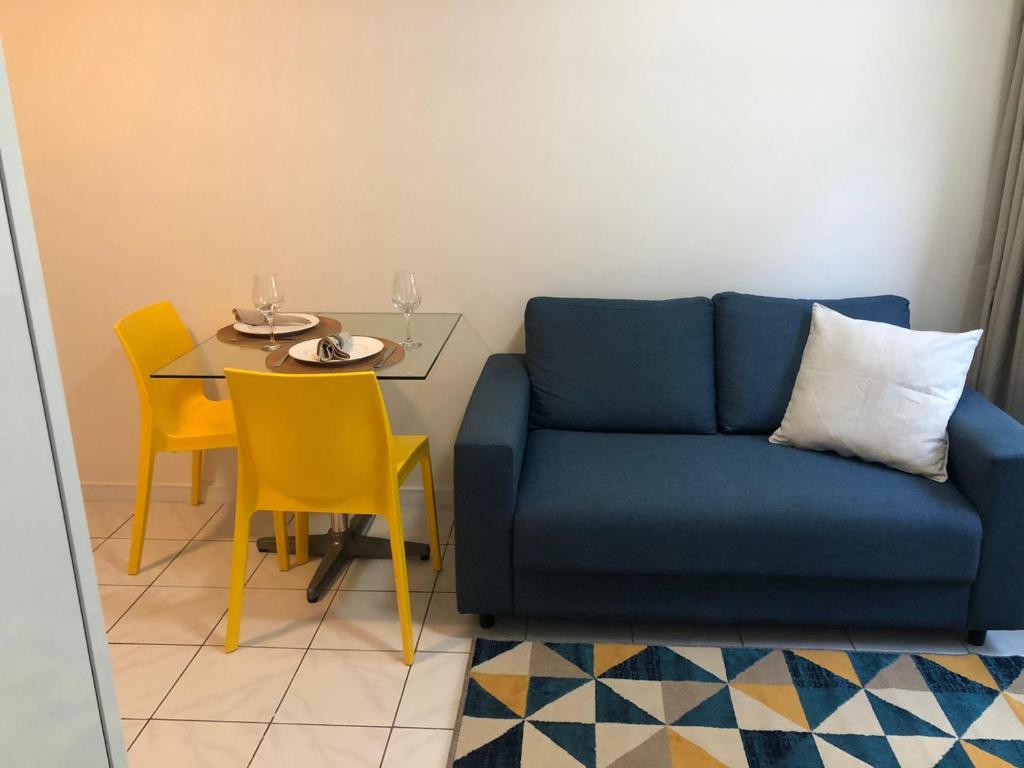 uma sala de estar com um sofá azul e uma mesa em Bilbao Residence no Recife