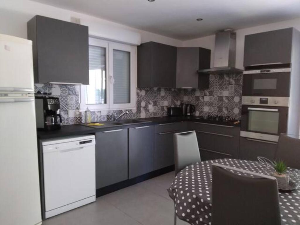 une cuisine avec des armoires grises et une table et un réfrigérateur blanc dans l'établissement La Truffière, à Foissac