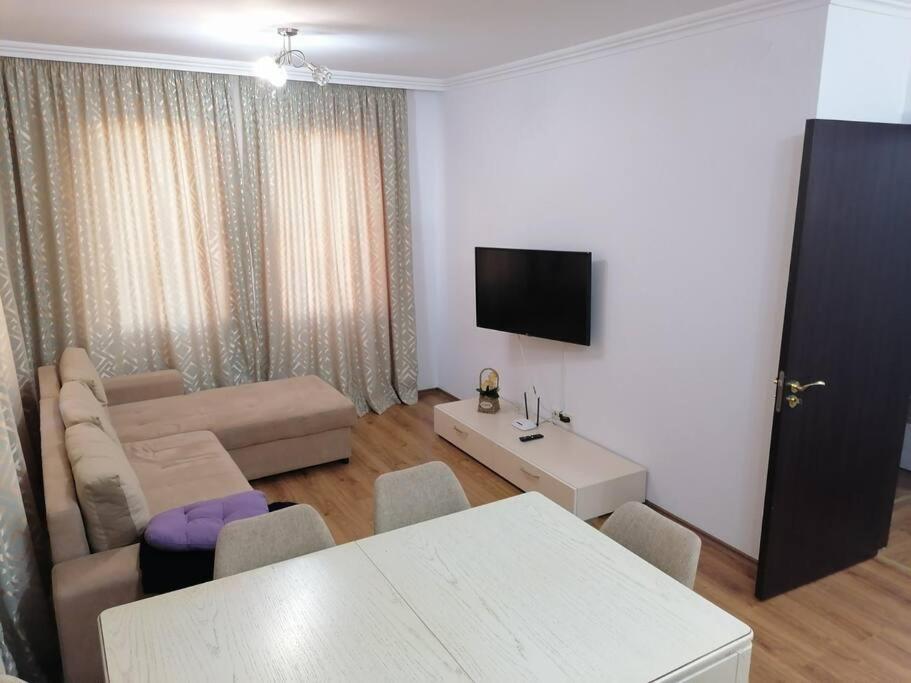 a living room with a couch and a table and a tv at Олимп - апартамент с две спални in Sveti Vlas