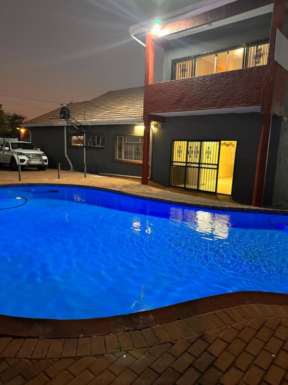 a blue swimming pool in front of a building at night at L-PACK PRIMROSe in Germiston