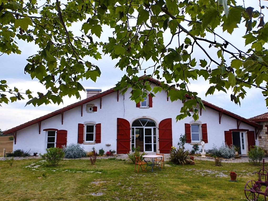 ein weißes Haus mit roten Rollläden und einem Hof in der Unterkunft La Coquille in Pouillon