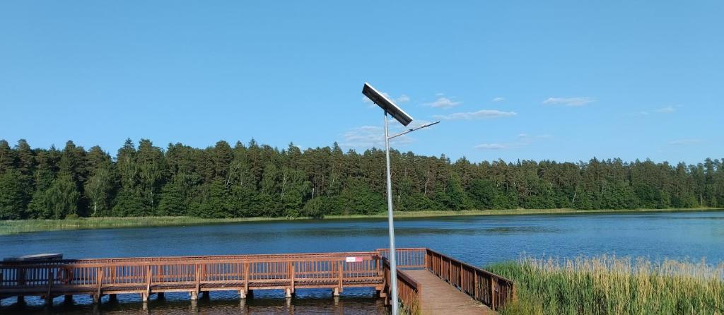 a wooden dock with a street light next to a lake at Bajkowy Dom in Mielno