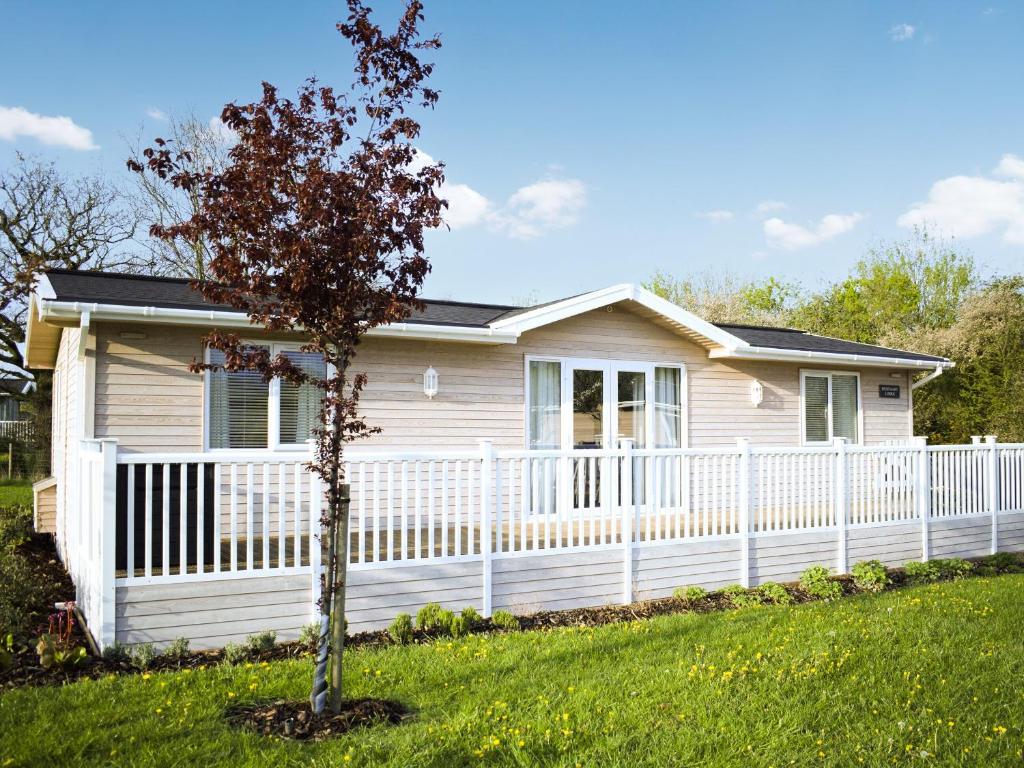 a white fence in front of a house with a tree at Rosemary Lodge in Willington