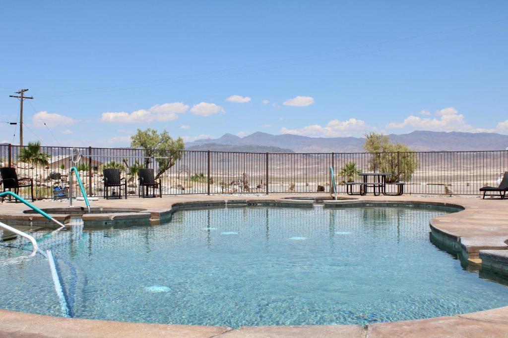 a swimming pool with a fence and mountains in the background at Death Valley Hot Springs in Tecopa