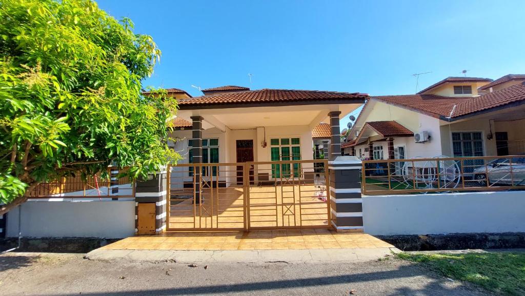 dom z bramą przed nim w obiekcie Teratak Azhan Homestay w mieście Kampong Sungai Putat
