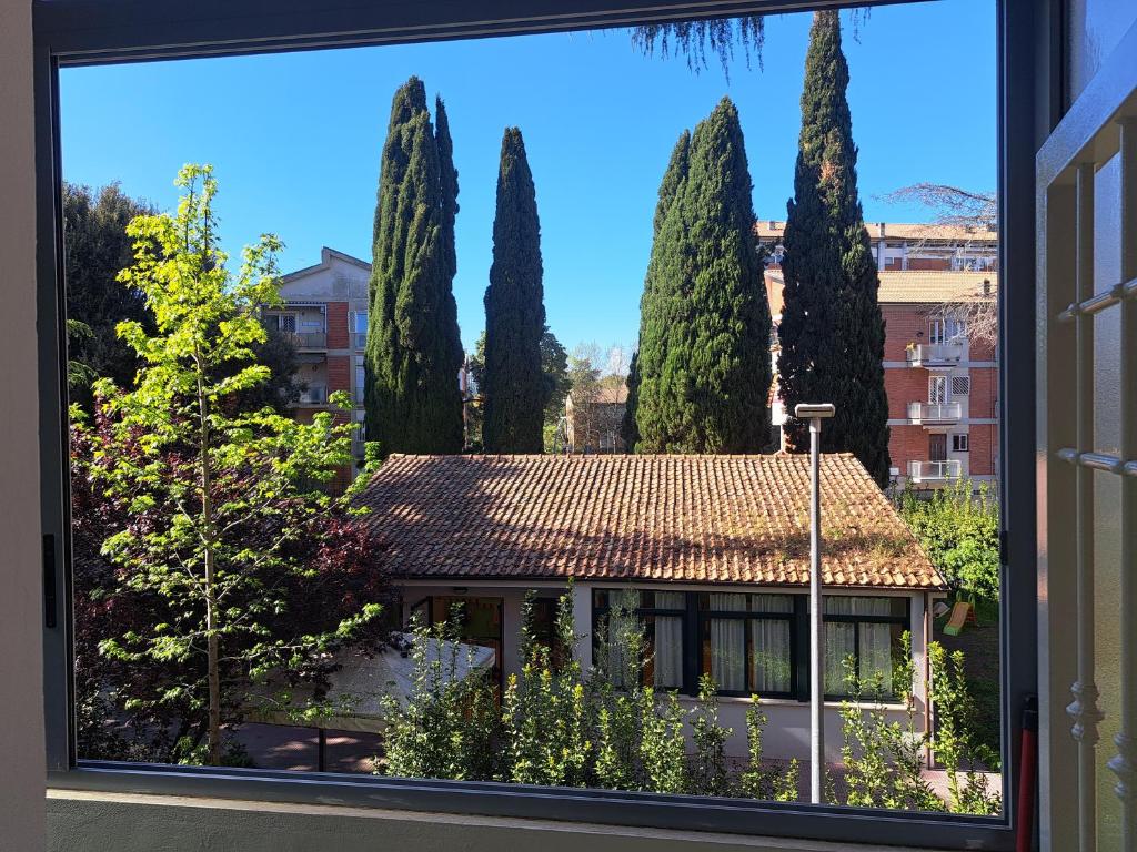 una ventana con vistas a una casa con árboles en La dimora dei Cedri Argentati, en Roma