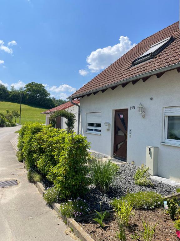 een wit huis met een bruine deur en struiken bij Apartment Schendel in Tettnang