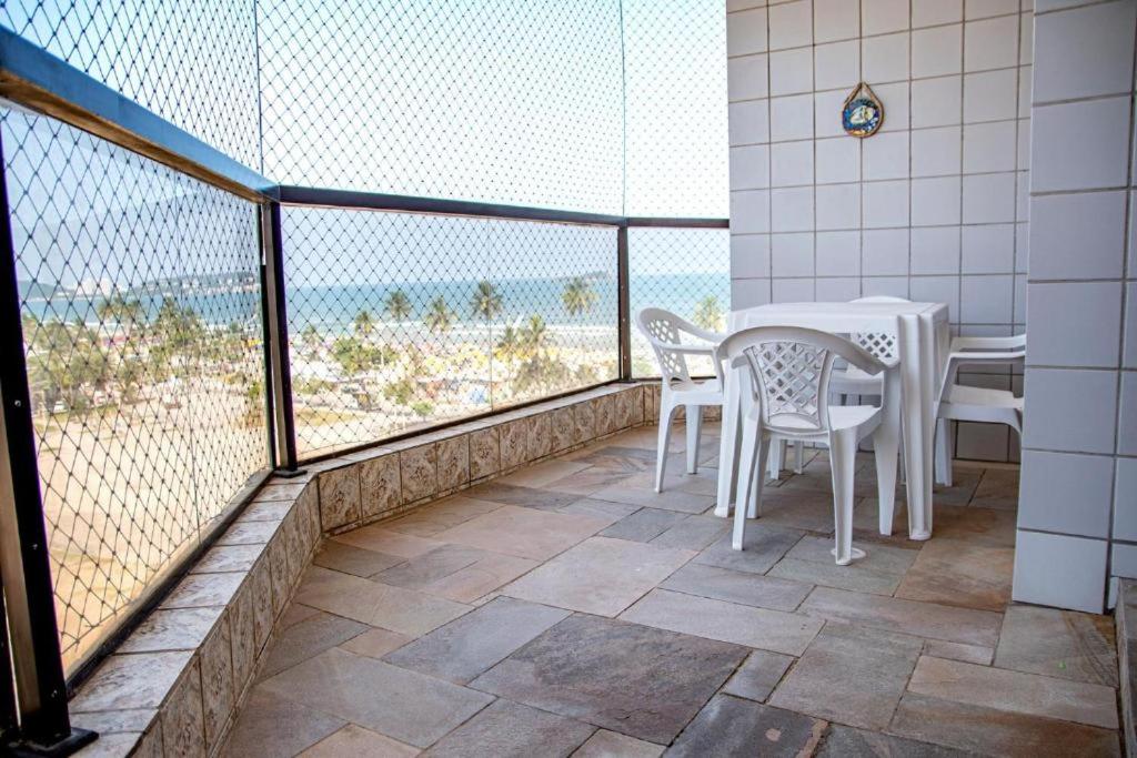 een balkon met een tafel en stoelen en de oceaan bij joia da enseada, com serviços de praia, de frente para o mar, 3 quartos, TV smart, piscina, academia, salão jogos, brinquedoteca, estacionamento in Guarujá