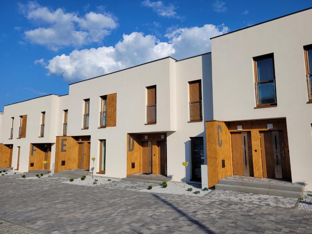 una fila de edificios blancos con puertas de madera en Leszka Loft Apartment en Wodzisław Śląski