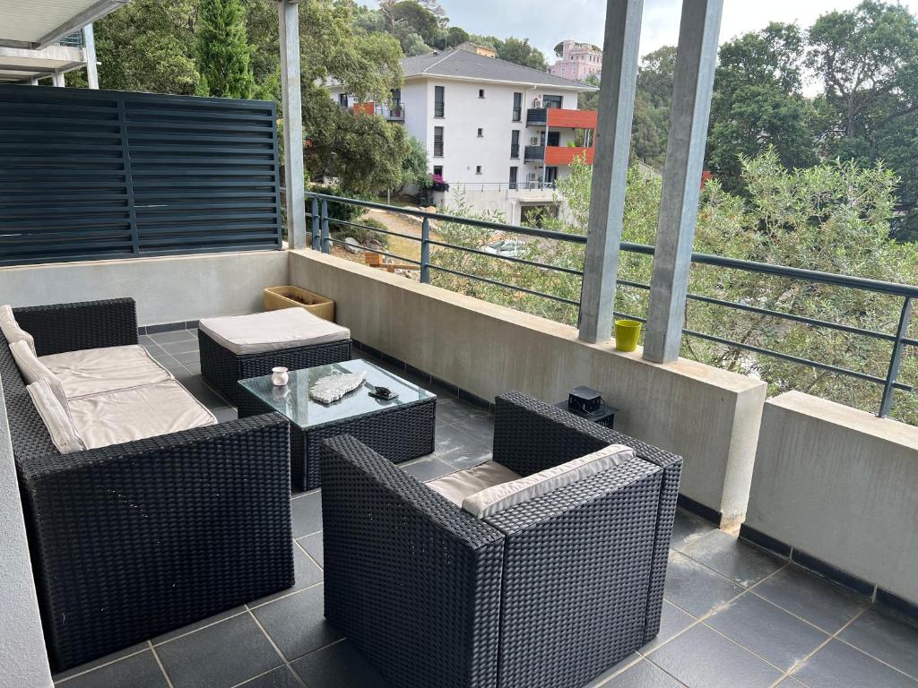 a balcony with wicker chairs and a coffee table at T2 avec très grande terrasse in Bastia