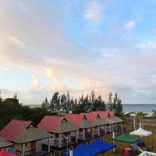 a row of buildings with red roofs next to the ocean at Bungalow le Charme, au bord de la mer in Marofarihy