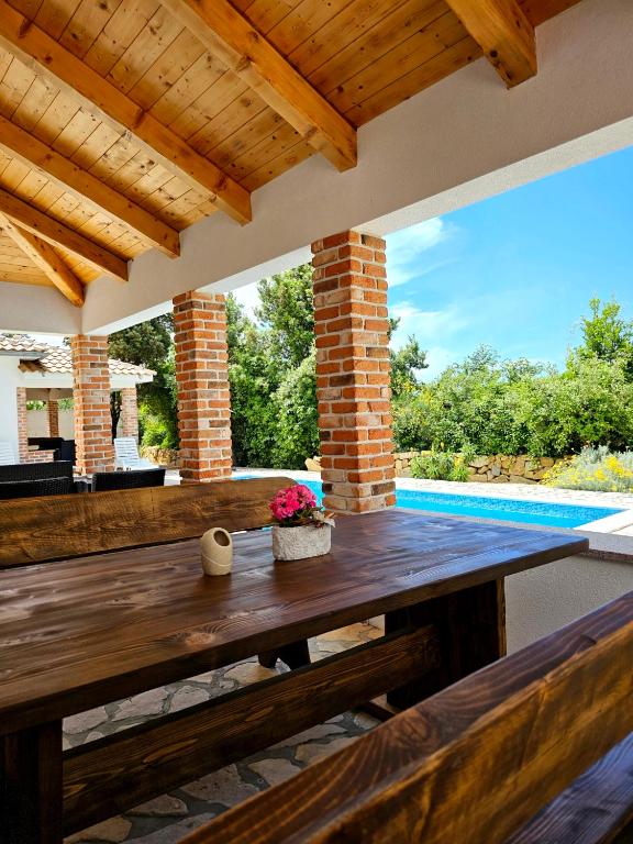 a patio with a wooden table and a swimming pool at Holiday homes Sintija in Rab