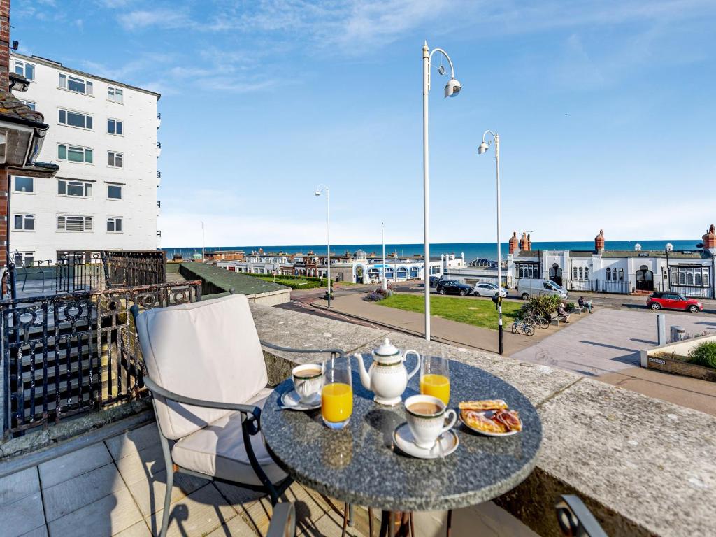 a table with food and drinks on a balcony with a view of the ocean at Crossways Mansions in Bexhill
