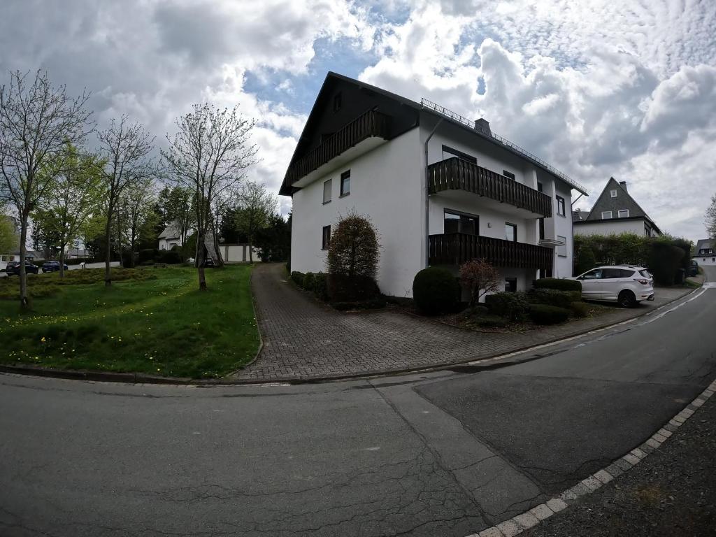 a white house with a black roof on a street at Moderne 3 Zi Ferienwohnung in Winterberg