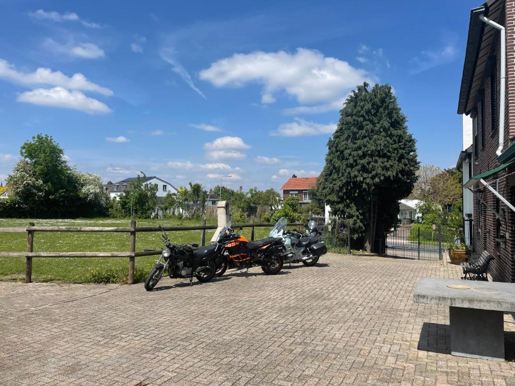 dos motocicletas estacionadas en un estacionamiento junto a una valla en Charming authentic renovated farm, en Cadier en Keer