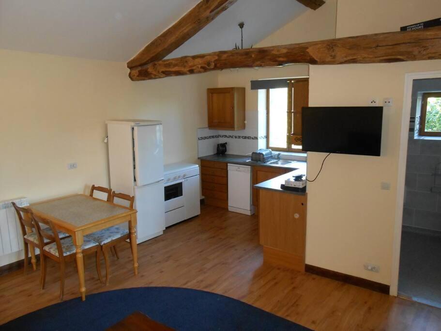 a kitchen with a table and a white refrigerator at Millstone Gite 2, two bed apartment + shared pool in Chassenon