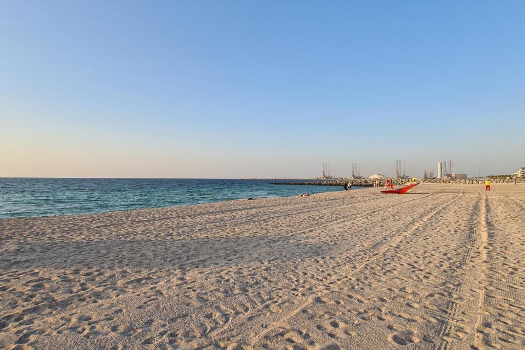 a beach with footprints in the sand and the ocean at Beachfront 1Bedroom Holiday Home at Port De La Mer in Dubai