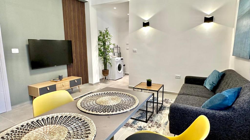 een woonkamer met een bank en een tafel en stoelen bij Cool one-bedroom Limeapartment with balcony in Haifa in Haifa