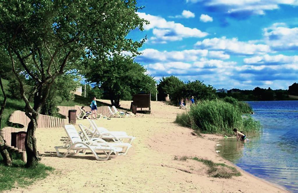 a group of lounge chairs on a beach next to the water at Gilužio Rivjera in Vilnius