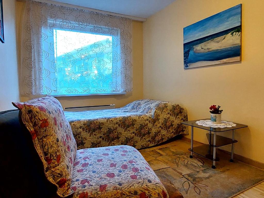a room with two beds and a chair and a window at Butas Miško slėnis in Juodkrantė