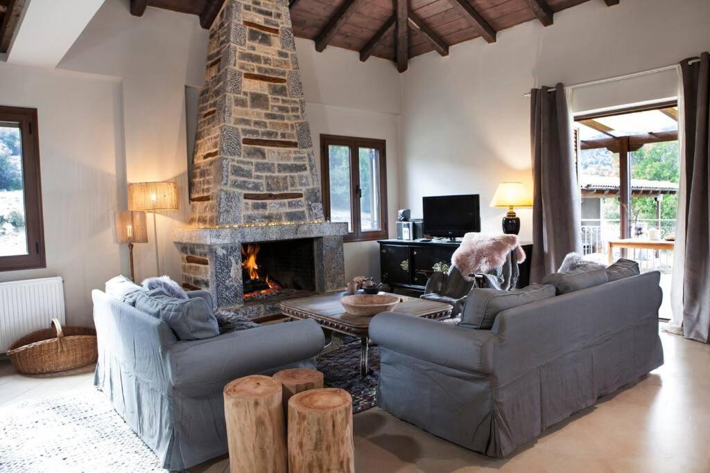 a living room with two couches and a stone fireplace at Bezeniko Amazing Arcadian Property! in Vlakhérna